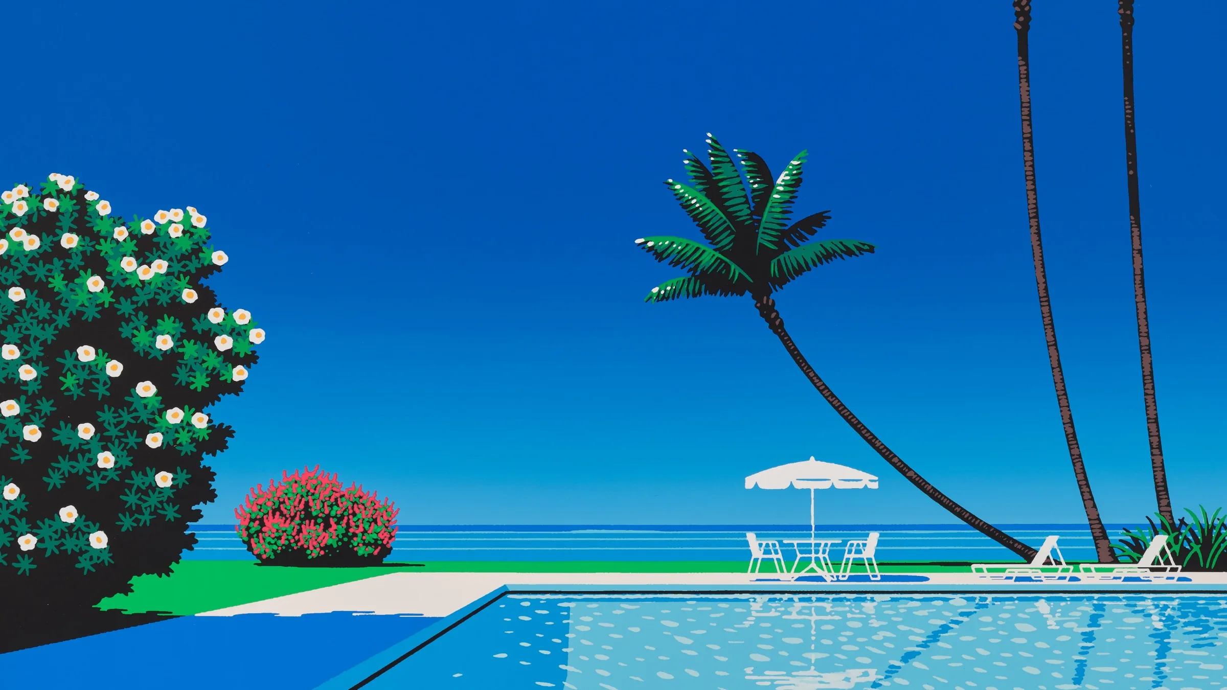 A poolside by the ocean under a deep blue sky: a leaning palm tree, a white parasol and a flowering bush.